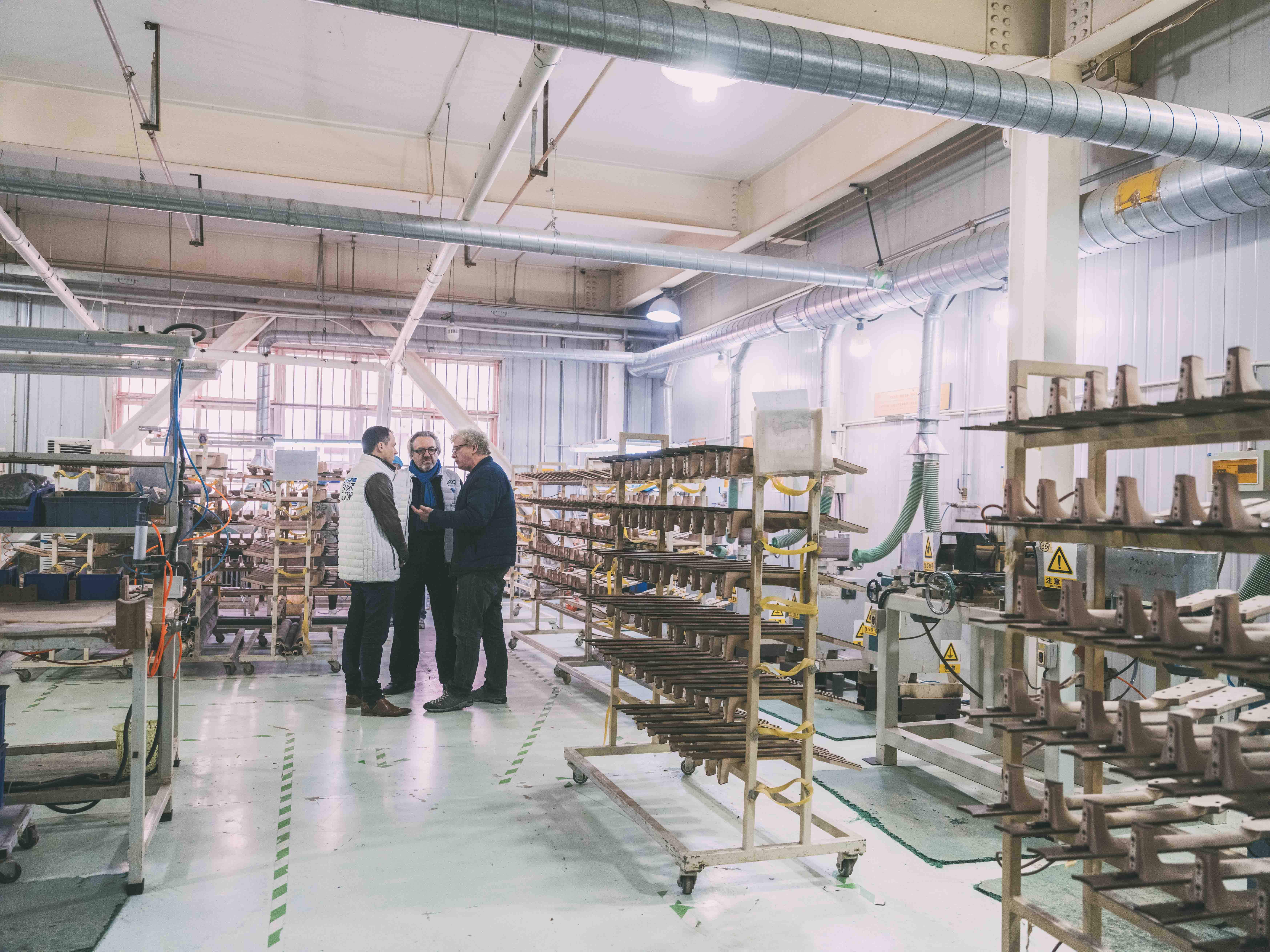 Gérard Garnier, Président de Lâg Guitars, Maurice Dupont, luthier et Meilleur Ouvrier de France, et Steve Kim, directeur de l'usine Lâg, discutent dans les allées de l'usine Lâg à Tianjin