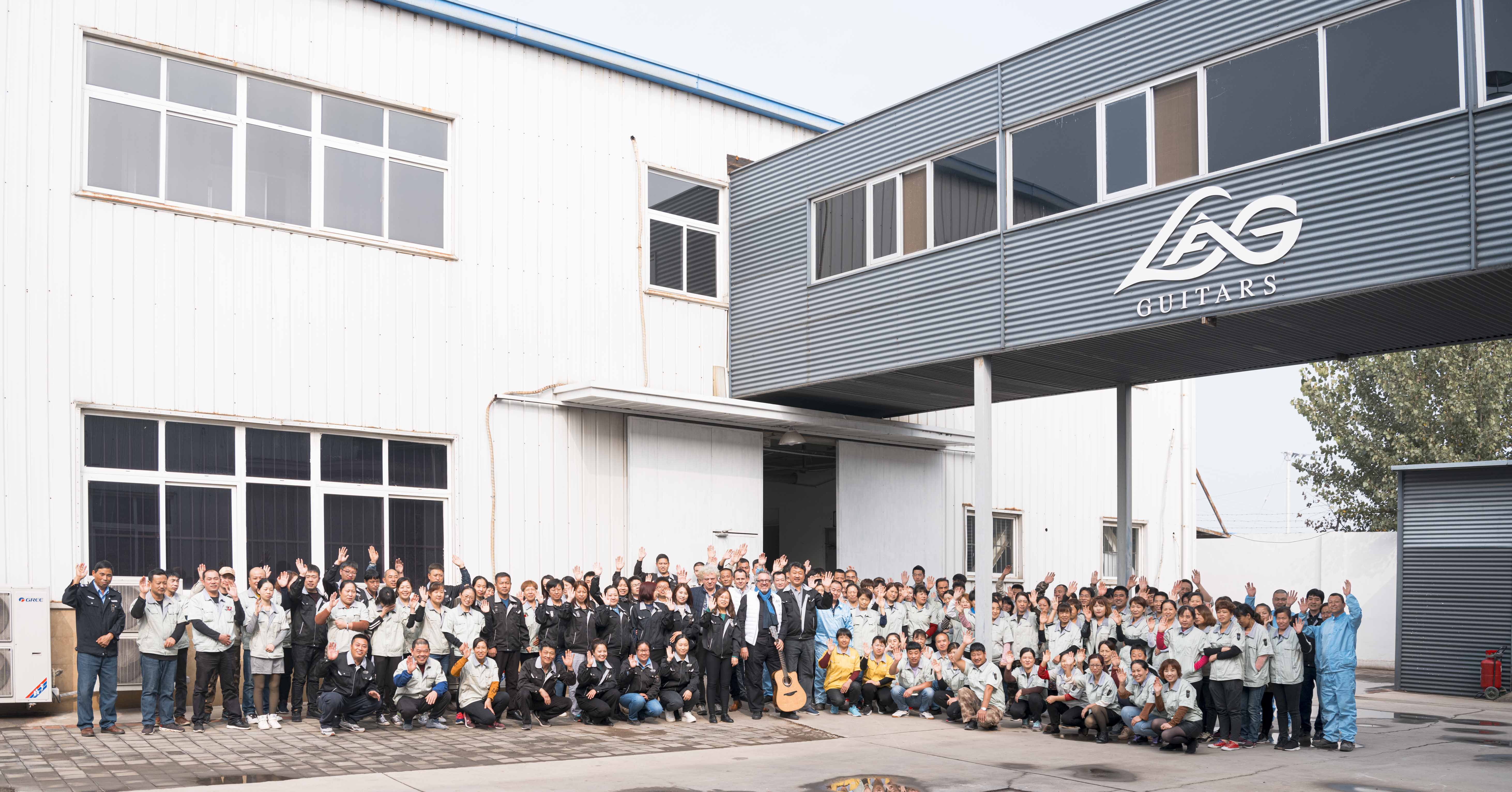 L'ensemble des employés de l'usine Lâg posent et saluent la caméra devant l'entrée de l'usine Lâg à Tianjin