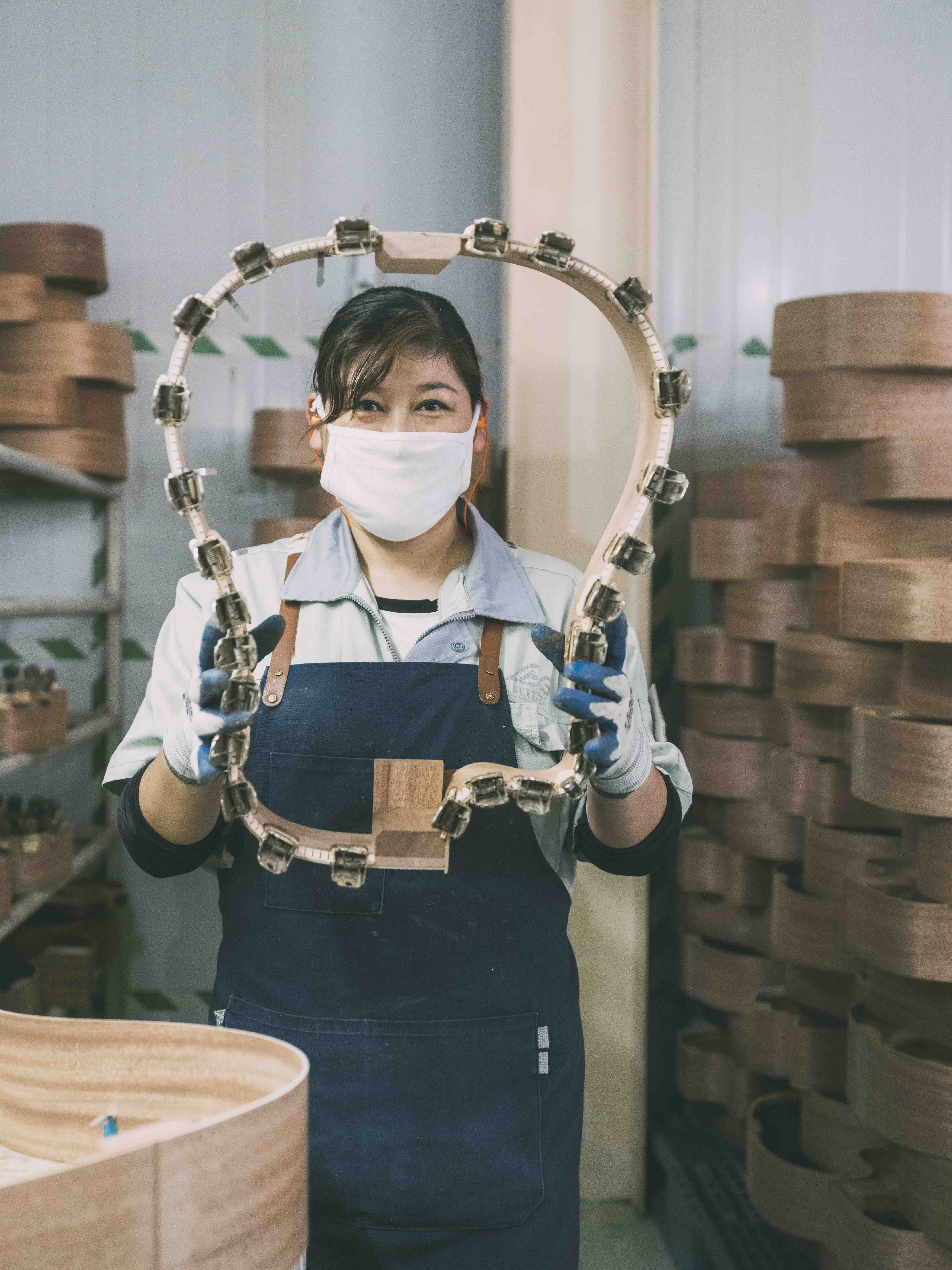 Une femme tient des éclisses de guitare Lâg dans l'usine Lâg