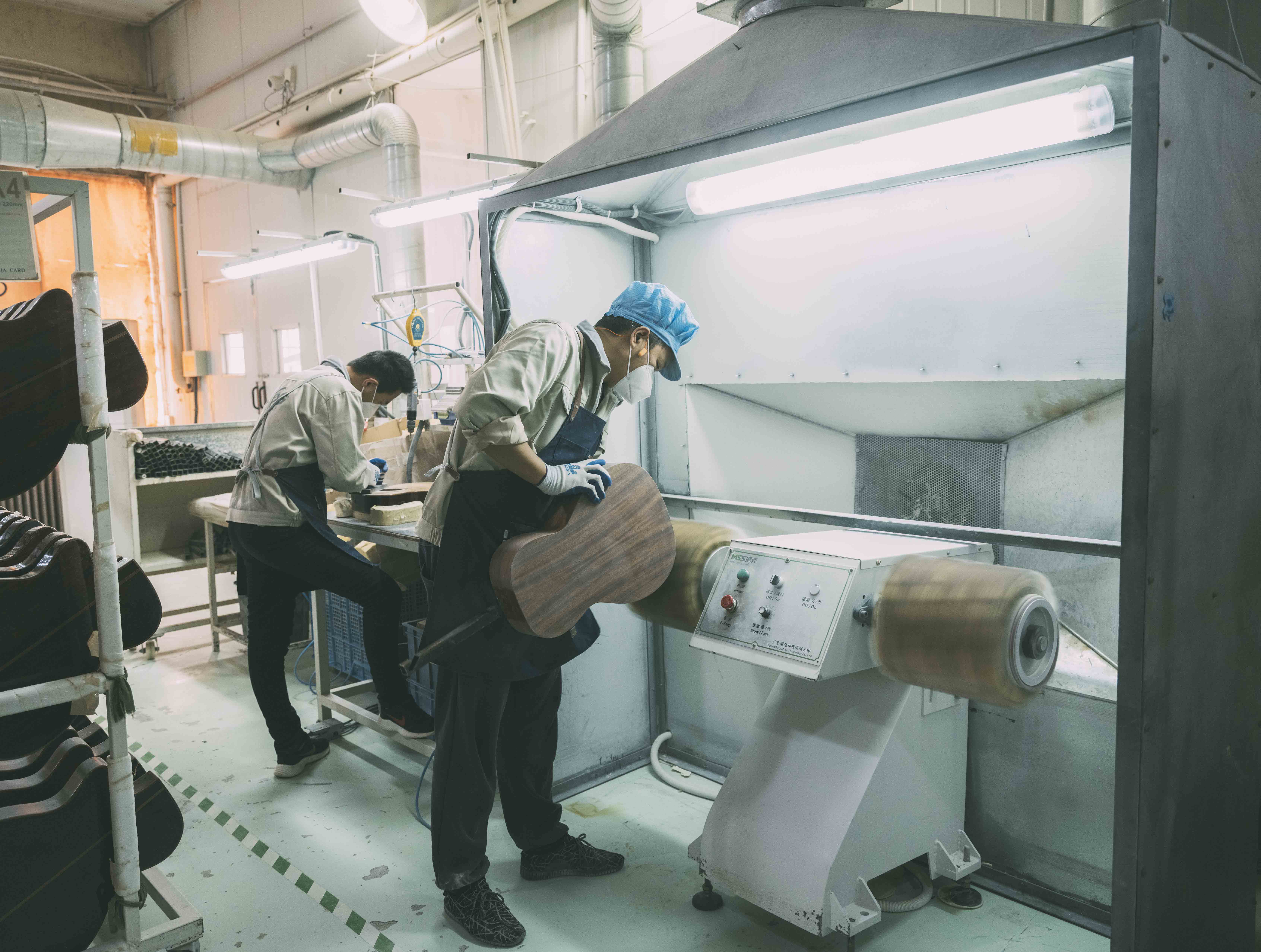 Deux employés de l'usine Lâg à Tianjin polissent les éclisses d'une guitare Lâg