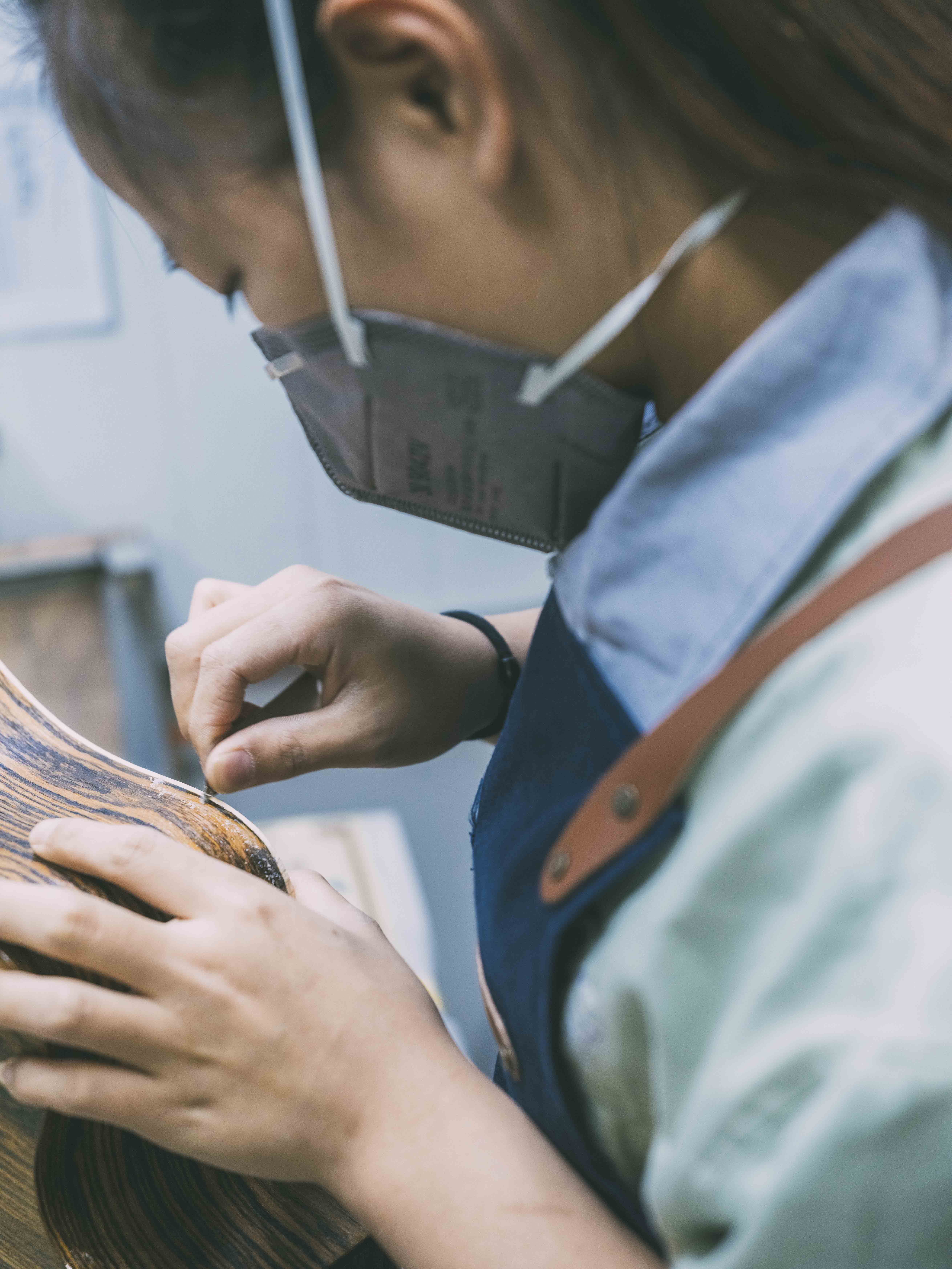 Une femme applique les détails de finitions à la main aux bordures arrondies d'une guitare SmartLâg HyVibe dans l'usine Lâg à Tianjin